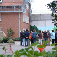 Foto einer Besuchergruppe vor dem Haus 1 und der bemalten Anstaltsmauer (Zum Artikel Informationsveranstaltungen)