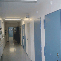 Foto, dass einen Flur im Hafthaus der Sozialtherapie zeigt. Auf der rechten Seite sind blaue, verschlossene Haftraumtüren (Zum Artikel Unsere Zuständigkeit)
