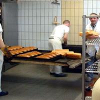 Drei Bäcker holen frisch gebackene Brote aus dem Ofen (Zum Artikel über die Bäckerei)