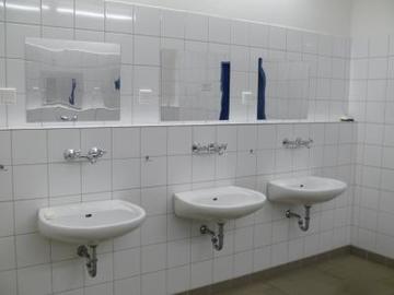 Foto, das einen Waschraum mit drei Waschbecken nebst Spiegel im Vollzugshaus 1 zeigt (Zum Artikel über die Abteilung Groß Hesepe). Suchsymbol Lupe