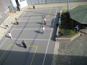 Das Foto zeigt ein Kleinspielfeld aus der Vogelperspektive auf dem Volleyball gespielt wird (Zum Artikel Sport und Freizeitangebote in der Hauptanstalt). Suchsymbol Lupe