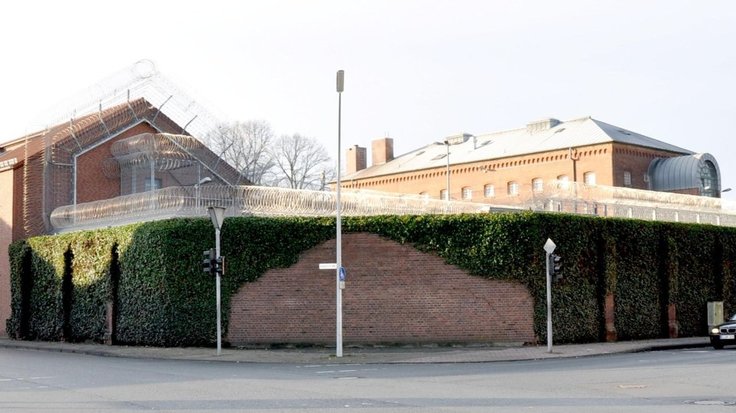 Foto, dass die Anstaltsmauer mit Mauerkronensicherung und die dahinter liegende Sozialtherapeutische Abteilung und das Hafthaus 3 zeigt.